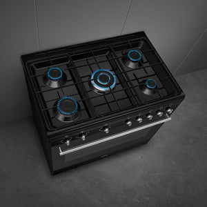 Black Smeg 90cm dual fuel range cooker with five burners and blue flame accents, available in Eastbourne and Uckfield with. - DB Domestics