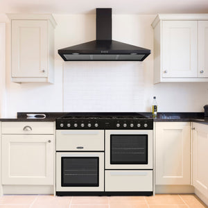 Cream Montpellier MDFRC100C 100cm dual fuel range cooker with black handles and dials, set in a modern kitchen with white. - DB Domestics