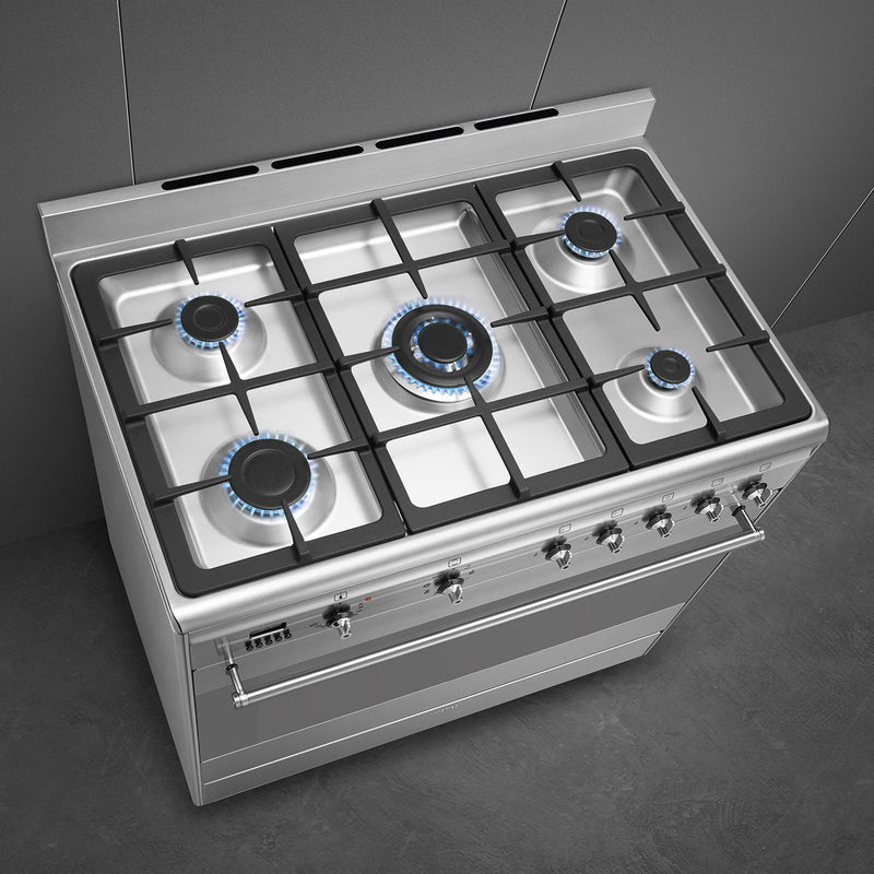 Smeg 90cm dual fuel range cooker in stainless steel with five burners, knobs, and cast iron pan supports, Free Delivery. - DB Domestics